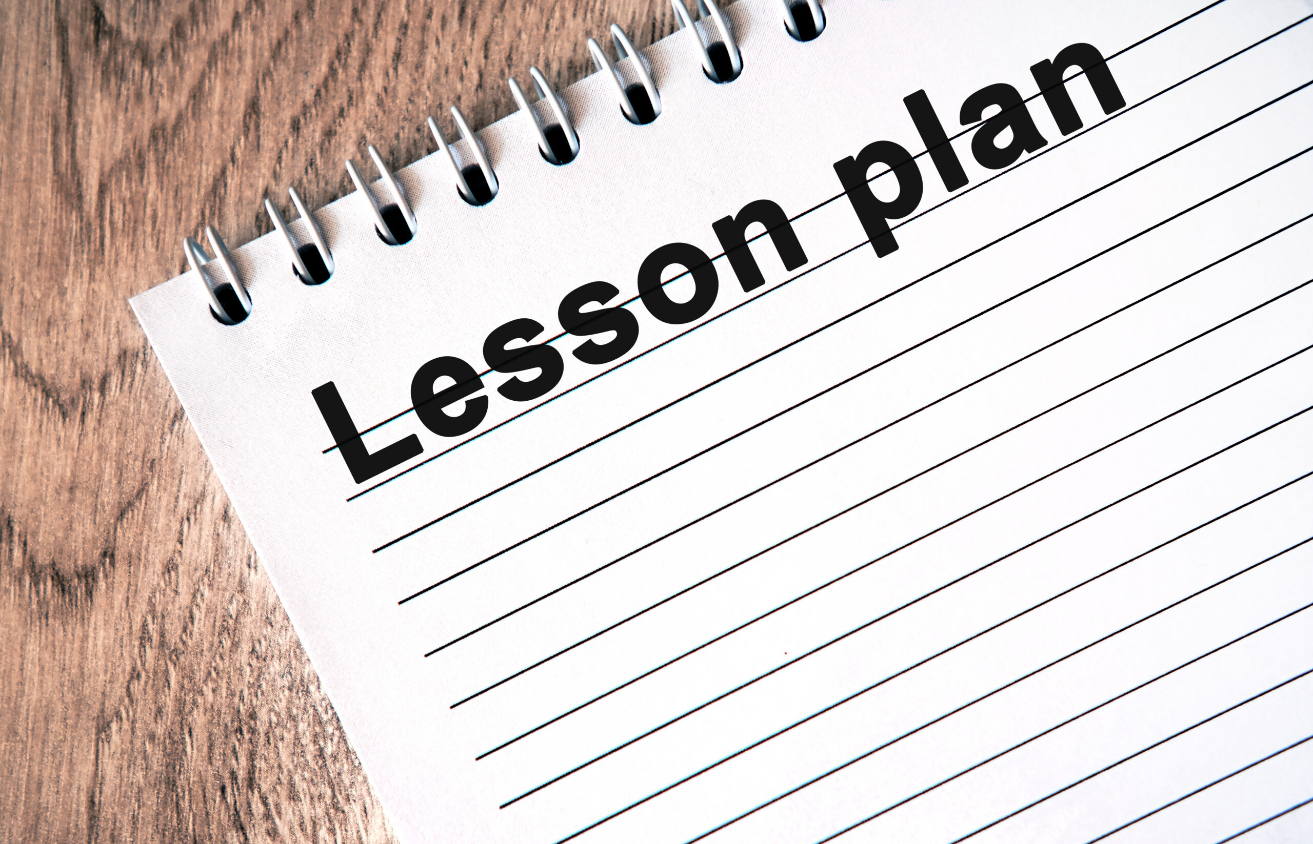 Close-up of a spiral-bound notebook page with the bold black text "organize lesson plans" written on the top line.